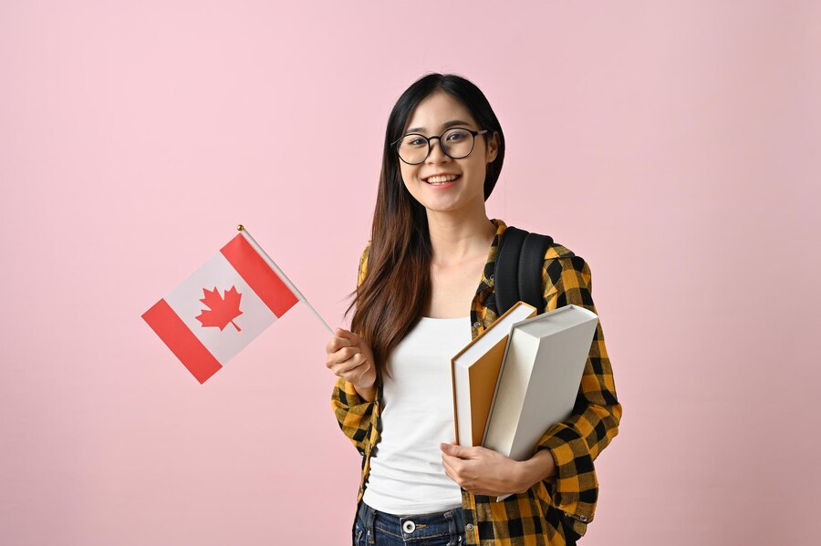 smiling-asian-female-college-student-holding-flag-canada-against-pink-isolated-background_67155-33062